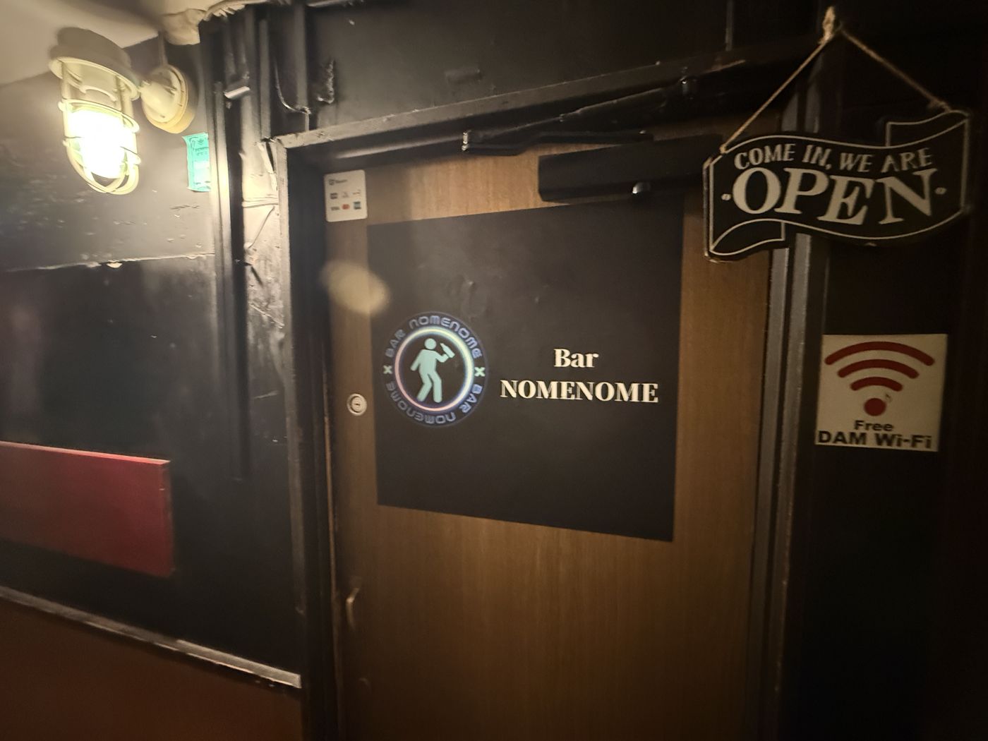 中銀新橋ビル地下1階のBAR NOMENOMEの入口。ロゴ入りの黒い看板と「OPEN」の札がかかった扉